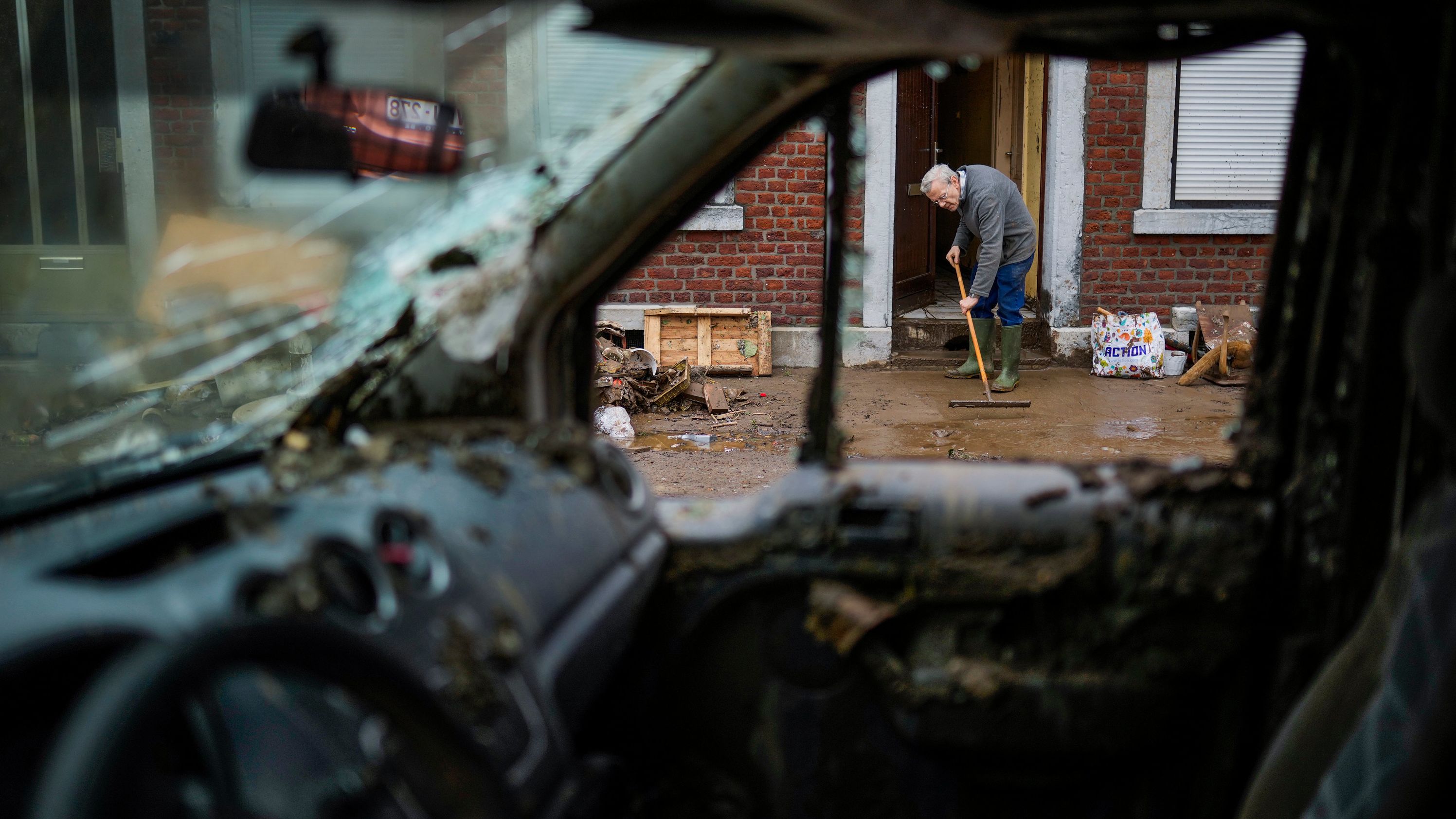 A man brushes water and mud out of his flooded house in Ensival, Belgium, on Friday.