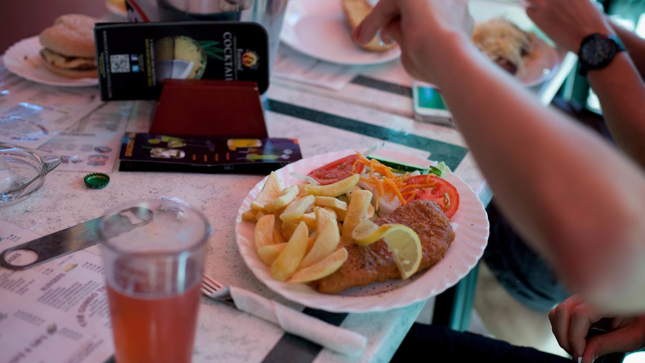 A man adds salt to his fish and chips in a British restaurant in Benidorm, Spain.