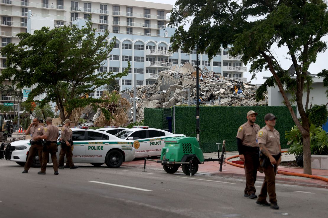 Miami-Dade police officers helping with the search and rescue stand near the completely collapsed 12-story Champlain Towers South on July 6, 2021 in Surfside, Florida. 