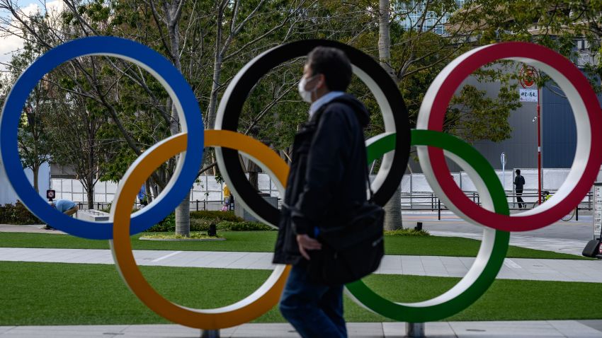 TOPSHOT - A man wearing a face mask walks in front of the Olympic Rings in Tokyo on March 11, 2020. - Japan and Olympic organisers are at pains to insist this summer's Games in Tokyo are on, despite the new coronavirus outbreak. (Photo by Philip FONG / AFP) (Photo by PHILIP FONG/AFP via Getty Images)
