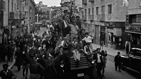 Jubilant residents in the Jewish part of Jerusalem ride a police car and wave what would become the Israeli flag as they celebrate the UN's 1947 decision to approve the partition of Palestine in the British Mandate for Palestine. (Photo by Hans Pins/GPO via Getty Images)