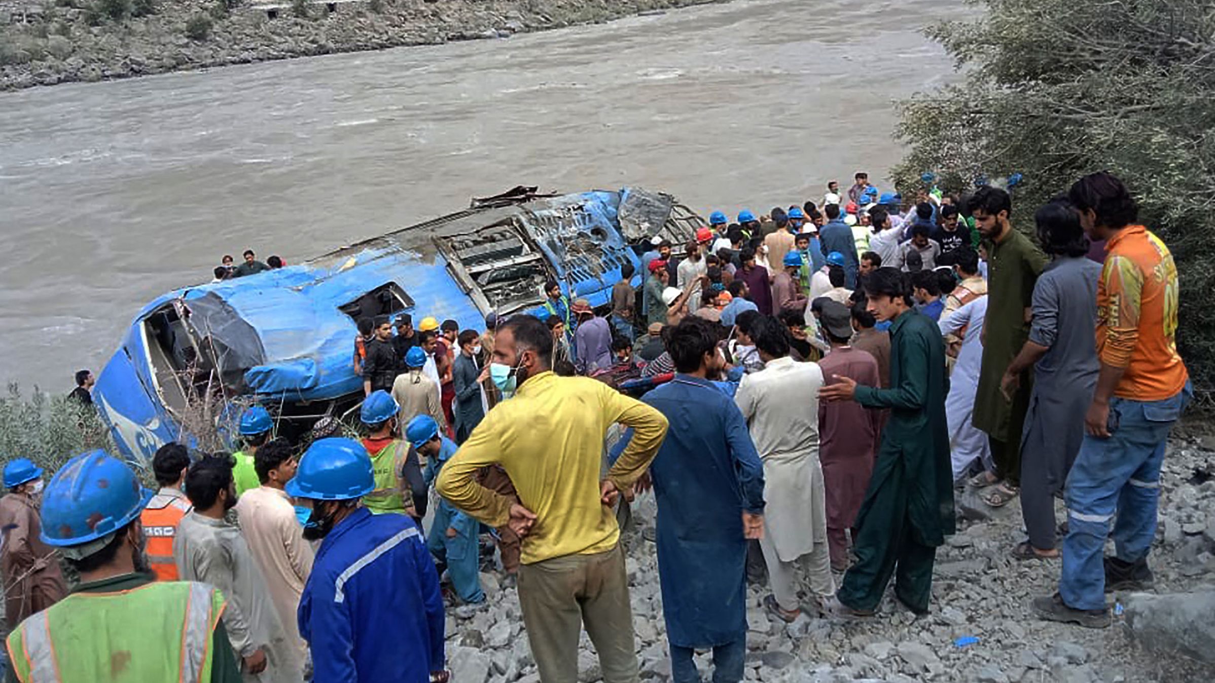 Rescue workers and onlookers gather around a wreck after a bus plunged into a ravine following an explosion in Pakistan on July 14.