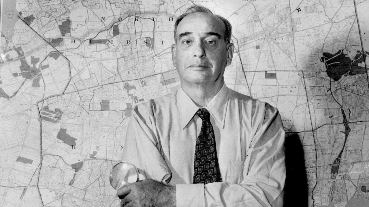 Robert Moses stands in front of map of Long Island, New York, in 1954.