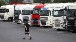 A driver passes a row of heavy goods vehicles (HGV) at a service station near Chafford Hundred, U.K., on Tuesday, July 13, 2021. Almost a third of U.K. logistics companies expect to face trucker shortages this year, and a 10th say recruitment issues will pose an "extreme barrier" to the recovery of their business from the pandemic. Photographer: Chris Ratcliffe/Bloomberg via Getty Images