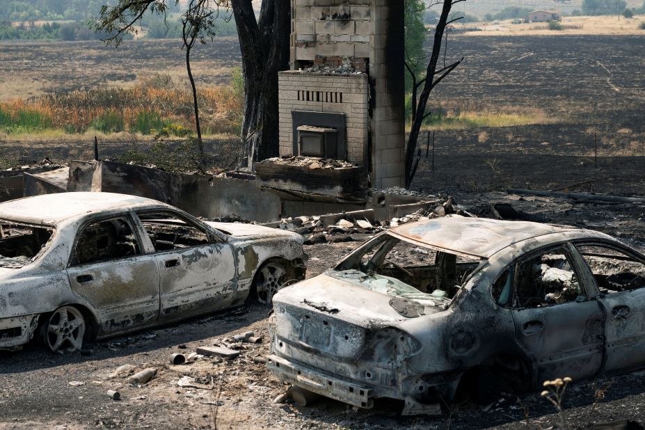 Burned cars sit outside a home that was destroyed by the Chuweah Creek Fire in Nespelem, Washington.