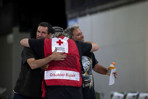Men hug a member of the Red Cross at a Bootleg Fire evacuation center in Klamath Falls, Oregon.