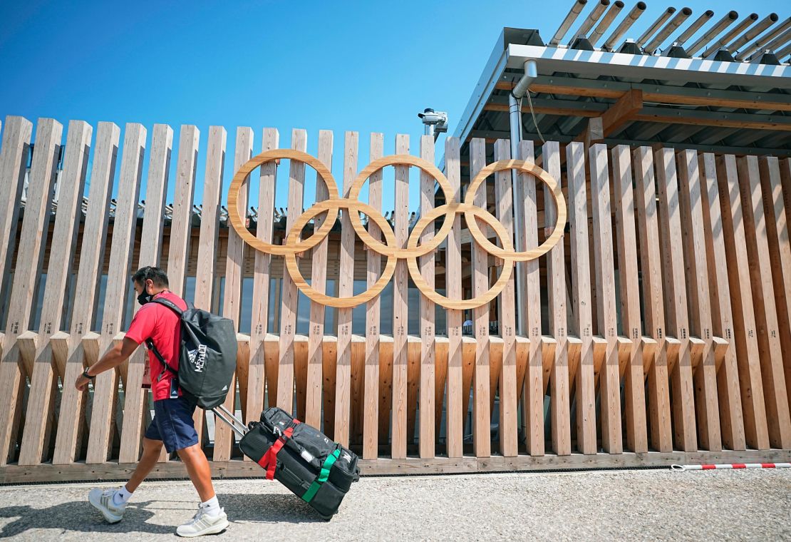 A man walks past Olympic rings at the entrance to Olympic Village.