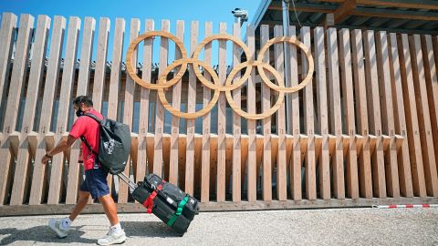 A man walks past Olympic rings at the entrance to Olympic Village.