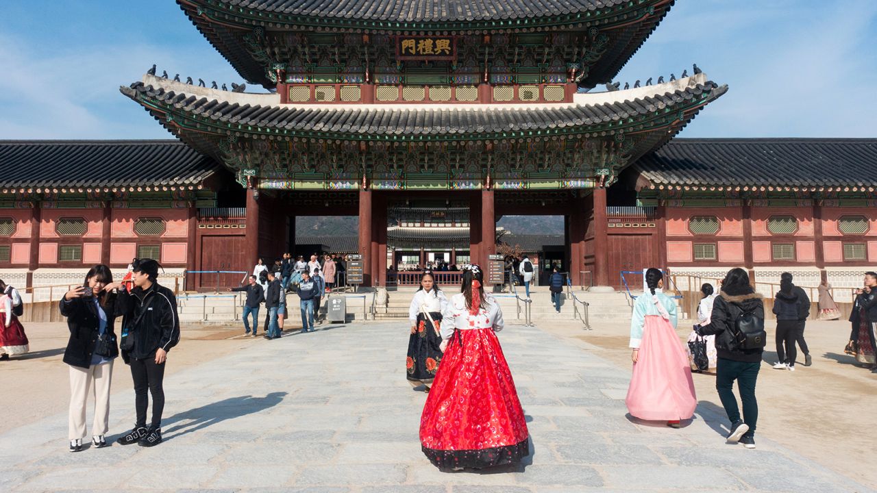 Travelers, some of whom are wearing traditional hanboks, gather in Seoul.