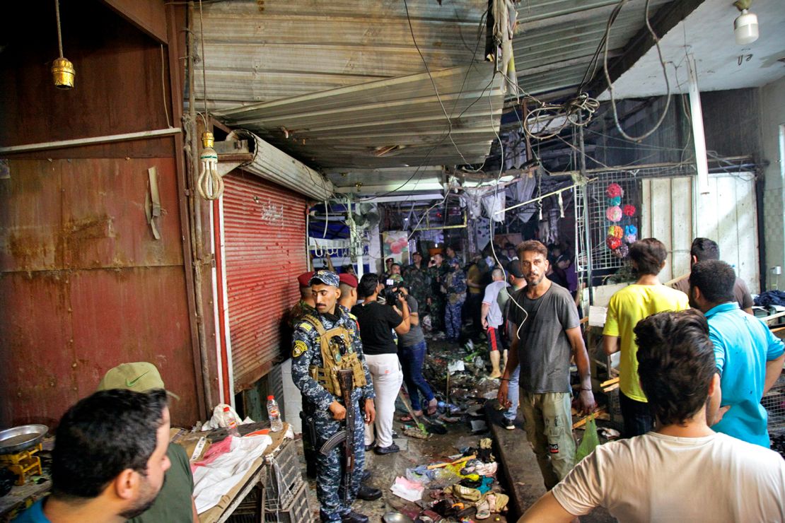 People and security forces gather at the site of a bombing in Wahailat market in Sadr City, Iraq, Monday, July 19, 2021.