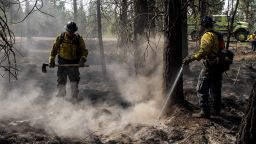 Firefighters Andy Sandoval (L) and Dylan Bota (R) work to put out a hotspot at the Bootleg Fire in Bly, Oregon on July 17, 2021. - More than 2,100 firefighters were again struggling to contain the vast Bootleg Fire raging in southern Oregon, near the border with California. Some were forced to retreat as the fire spread amid the fourth intense heatwave of the summer. (Photo by Payton Bruni / AFP) (Photo by PAYTON BRUNI/AFP via Getty Images)