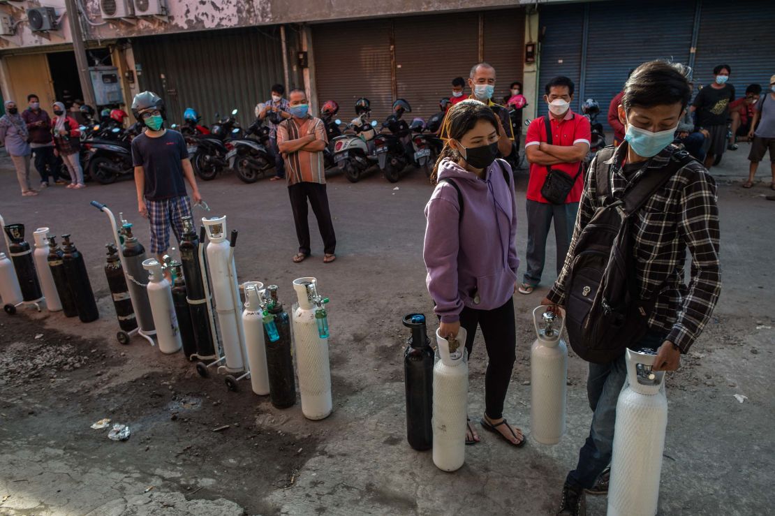 Residents queue up to get oxygen tanks refilled at a refilling station in Surabaya on July 15, 2021.