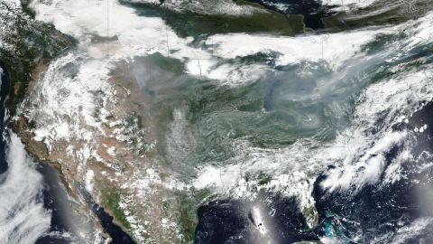 Smoke - the darker gray between the bright white storm clouds - can be seen from space over the Great Lakes and Northern Plains Monday, July 19.
