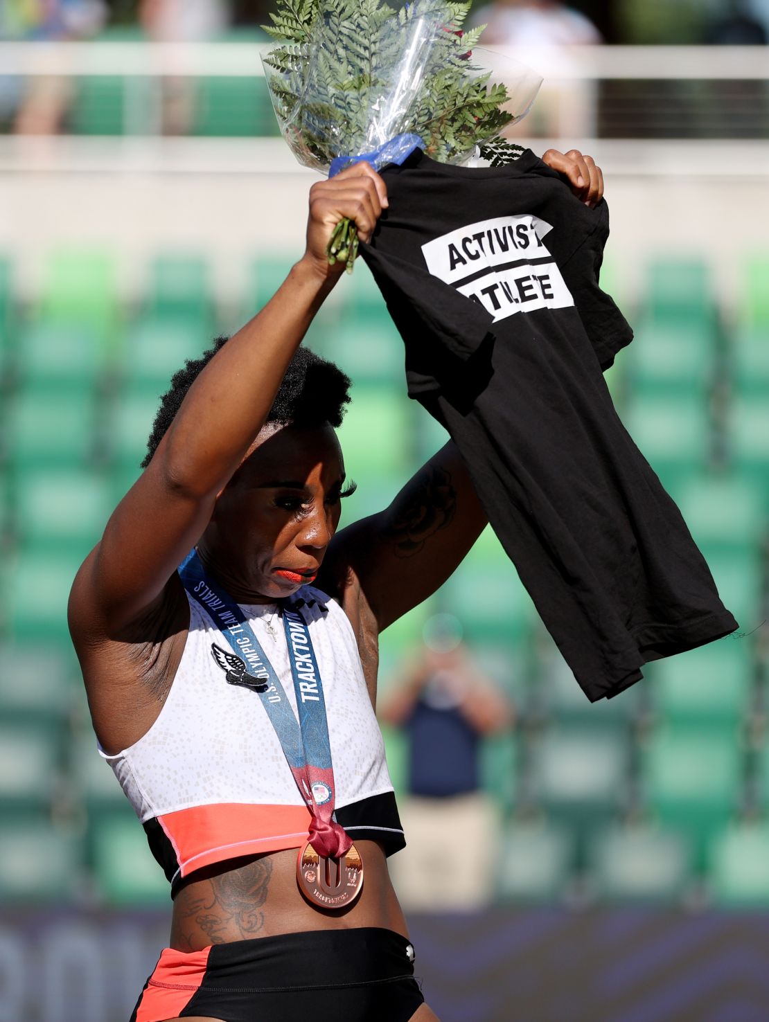 Gwen Berry holds up a shirt reading "Activist Athlete" as she celebrates finishing third in the Women's Hammer Throw final on day nine of the 2020 US Olympic Track & Field Team Trials on June 26, 2021.