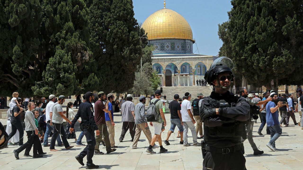 An Israeli police officer stands guard as Jewish men visit the Dome of the Rock on the Temple Mount/Haram al-Sharif compound, during the annual mourning ritual of Tisha B'Av (the ninth of Av) -- a day of fasting and a memorial day, commemorating the destruction of ancient Jerusalem temples, in the Old City of Jerusalem, on Sunday, July 18.