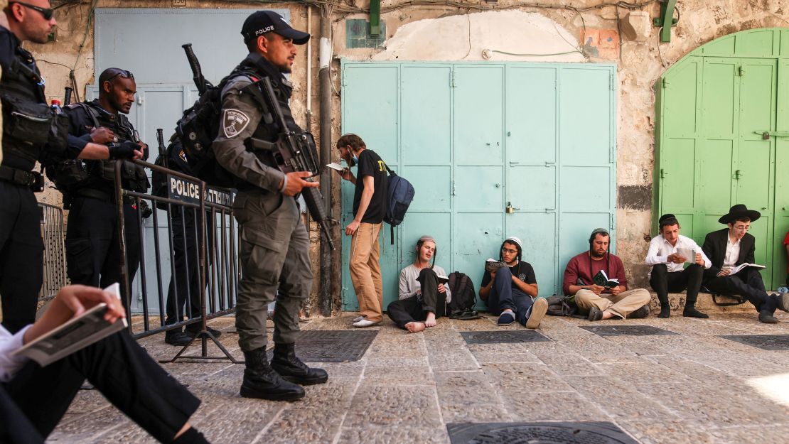 A group of Orthodox Jewish men pray outside one of the entrances to the Temple Mount/Haram al-Sharif, as Israeli security forces stand guard at a barrier, during the annual Tisha B'Av (Ninth of Av) fasting and memorial day, commemorating the destruction of ancient Jewish temples some 2000 years ago, on Sunday, July 18.