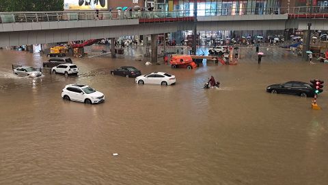 People stranded in flood waters along a street following heavy rains in Zhengzhou, China, on July 20.