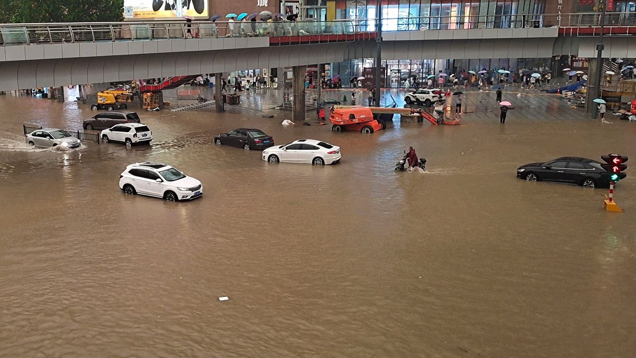People stranded in flood waters along a street following heavy rains in Zhengzhou, China, on July 20.