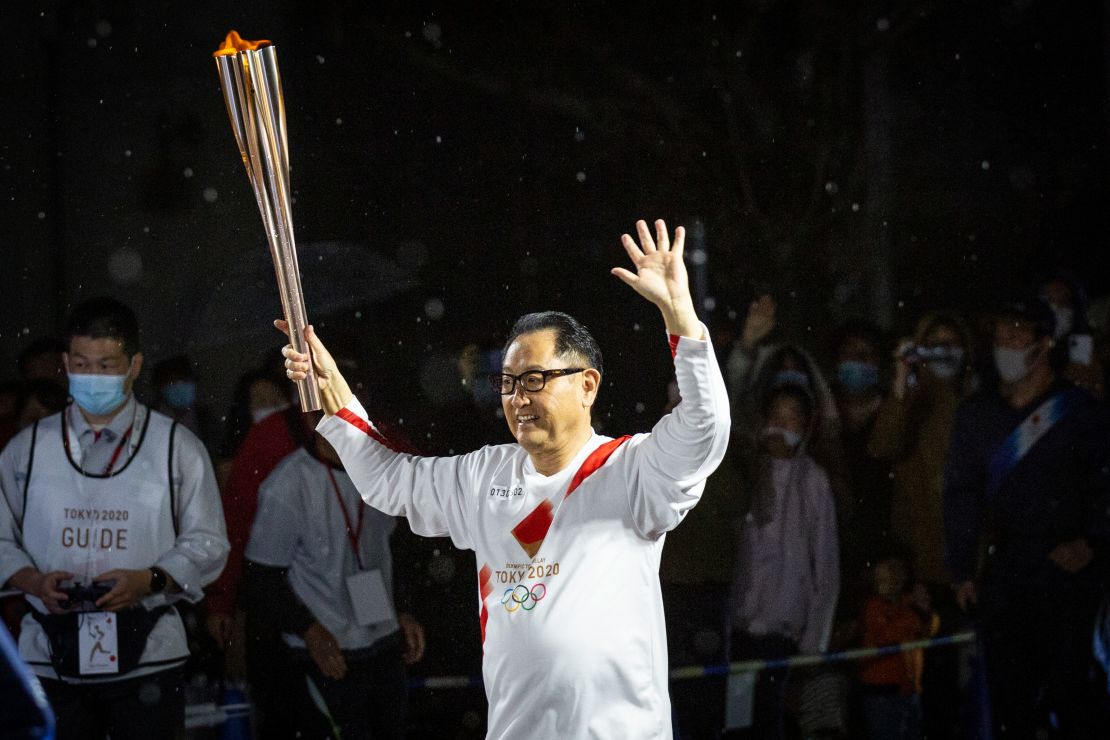 Toyoda runs with the Olympic torch during the Tokyo Olympic Games Torch Relay.