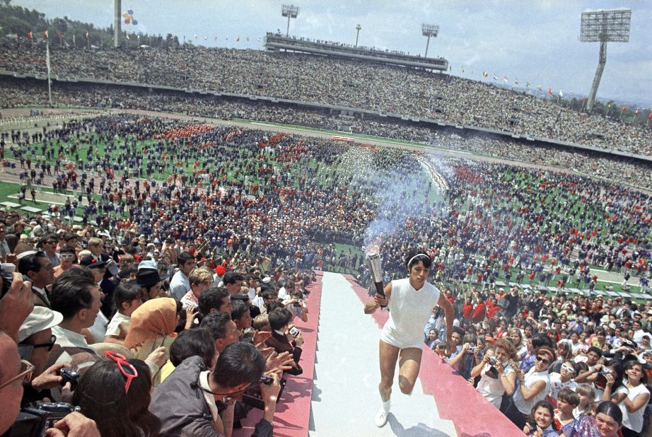 Sprinter Enriqueta Basilio, the first woman to light the Olympic flame, carries the torch during opening ceremonies for the Olympic Games in Mexico City.