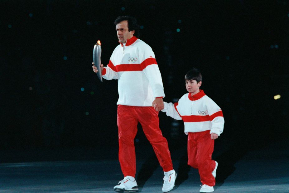 Former French soccer player Michel Platini and young skier Francois-Cyrille Grange walk with the Olympic torch during the 1992 Winter Olympic Games opening ceremony, in Albertville, France.