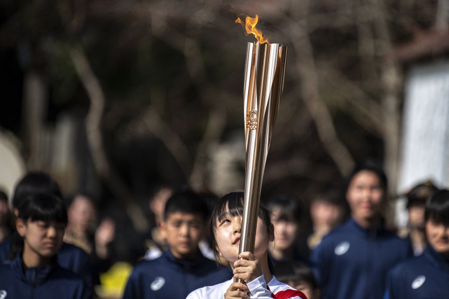 Torchbearer Rio Suzuki, a junior high school student, carries the Olympic torch at Somanakamura Shrine in the town of Soma, Fukushima Prefecture, ahead of the delayed 2020 Tokyo Summer Games.