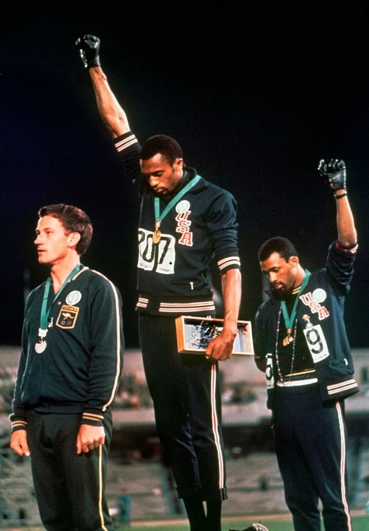 American athletes Tommie Smith, center, and John Carlos raise their fists and hang their heads while the US National Anthem plays during their medal ceremony at the 1968 Summer Games in Mexico City. Their gesture became front-page news around the world as a symbol of the struggle for civil rights. To their left stood Australian Peter Norman, who expressed his support by wearing an Olympic Project for Human Rights badge.