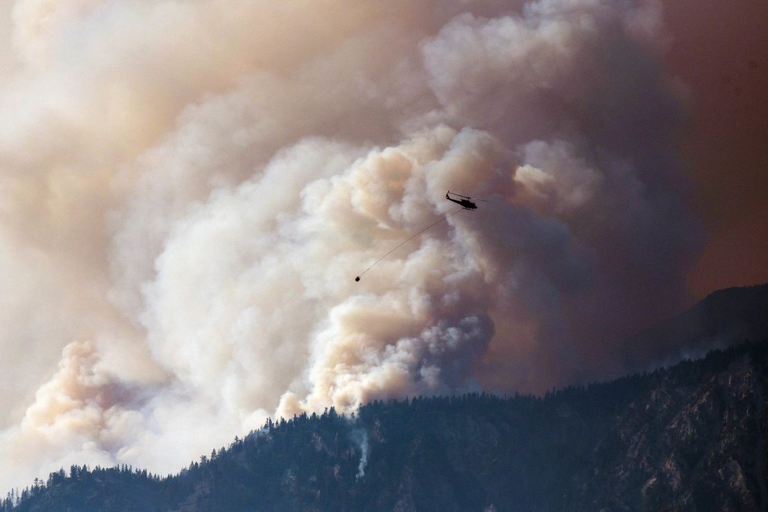 A helicopter prepares to make a water drop as smoke billows along the Fraser River Valley near Lytton, British Columbia, Canada, on Friday, July 2, 2021.