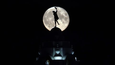 The full buck moon rises over a dancing lady on the Spanish City building in Whitley Bay, England, in July 2020. 