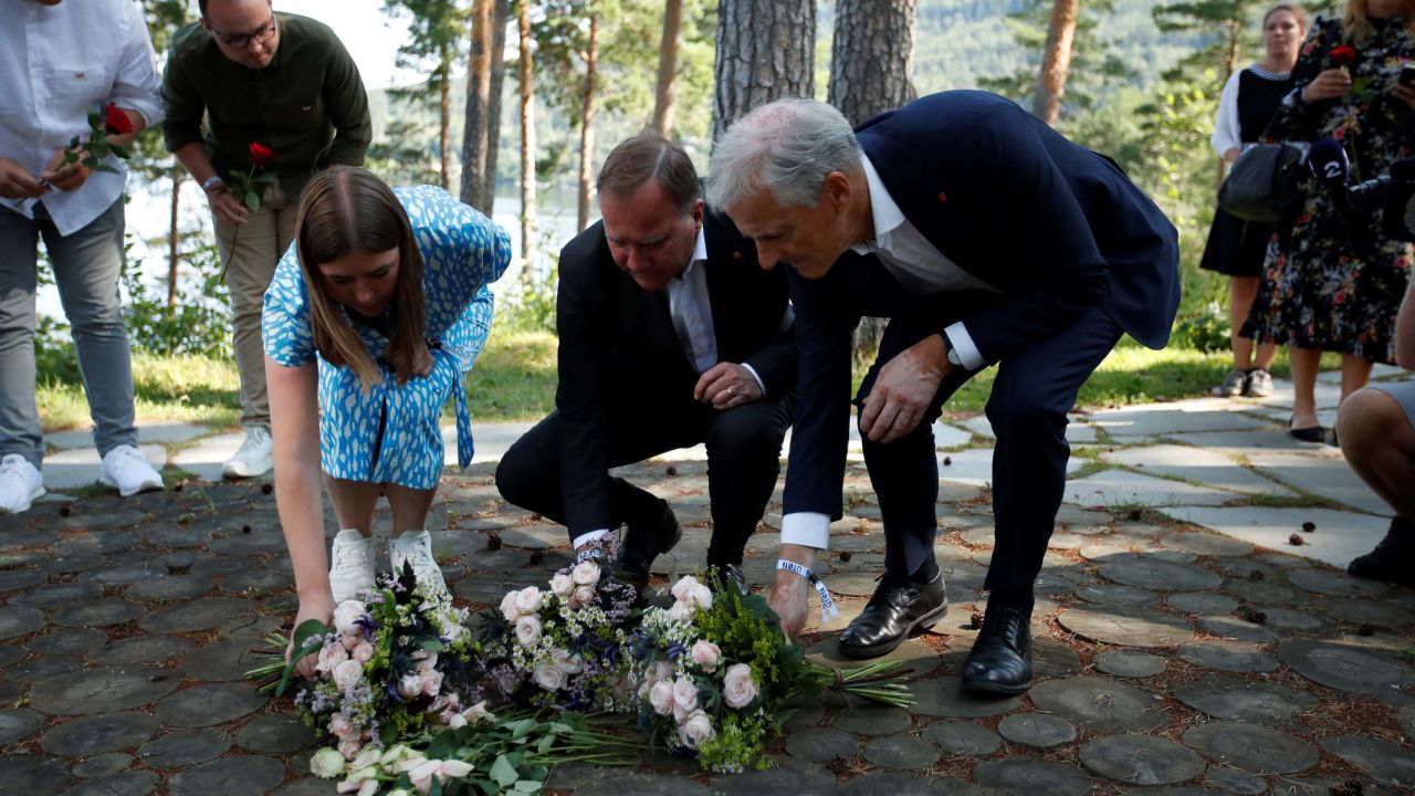 Leader of the youth organization of the Labour Party (AUF) Astrid Hoem, left, Swedish Prime Minister Stefan Löfven, center, and leader of the Norwegian Labor Party Jonas Gahr Store, right, lay flowers at a memorial on Utoya island, on July 21, 2021.