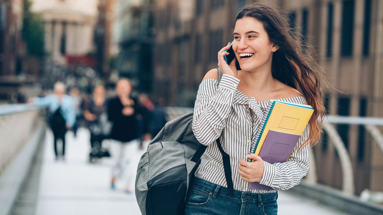 underscored college student walking with cell phone