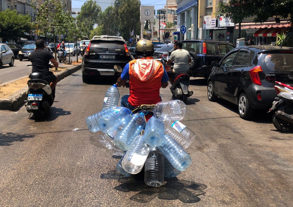 A man rides his scooter with empty water bottles to fill them with gasoline, in Beirut, on June 23, 2021. 