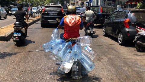 A man rides his scooter with empty water bottles to fill them with gasoline, in Beirut, on June 23, 2021.