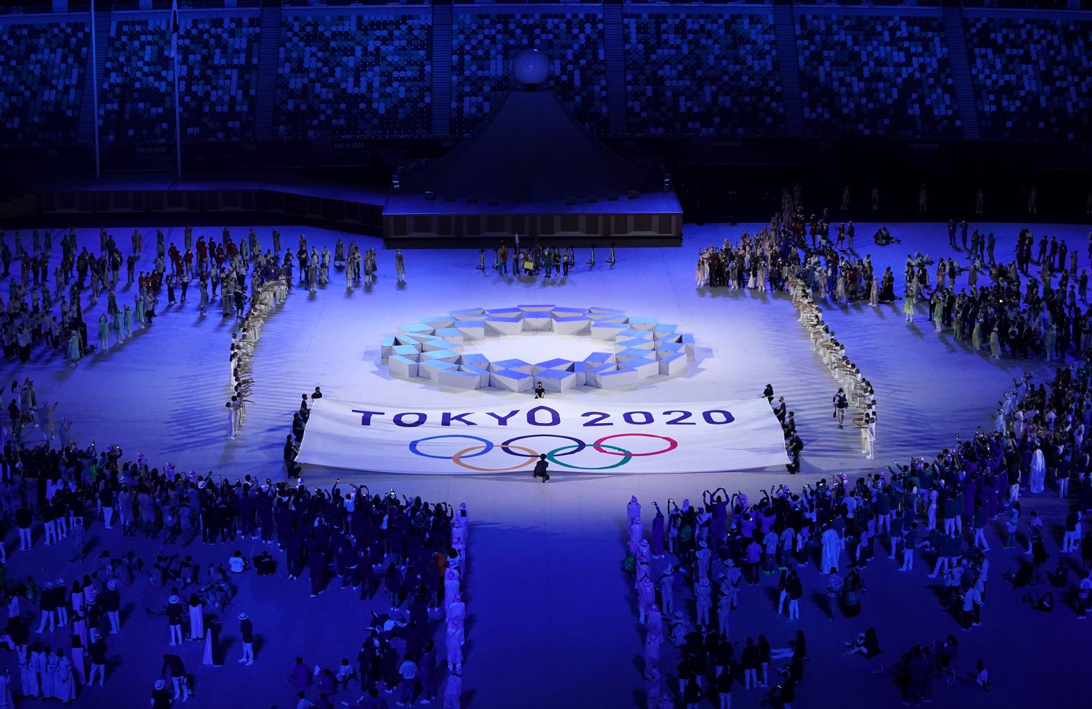 The Olympic teams from every country watch performers on stage.