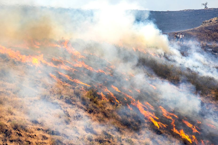 People stand behind the fire line as flames from the Steptoe Canyon Fire spread through dry grass in Colton, Washington, on July 22.