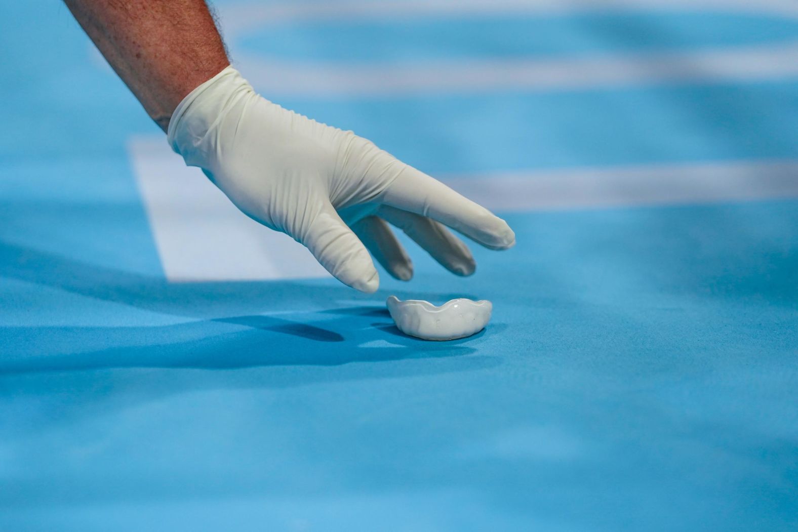 A staff member picks up the mouthguard of Great Britain's Peter McGrail during a boxing match on July 24.