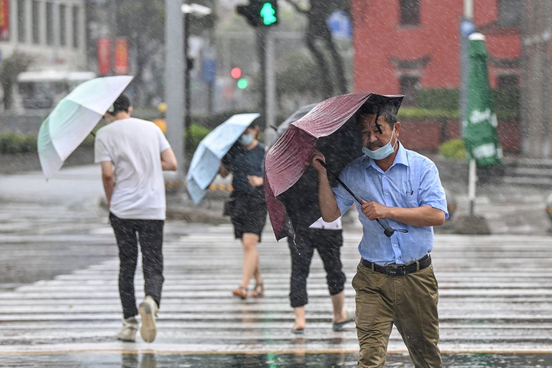 People cross the street in the wind and rain in Ningbo on July 25, as Typhoon In-Fa lashes the east coast of China.