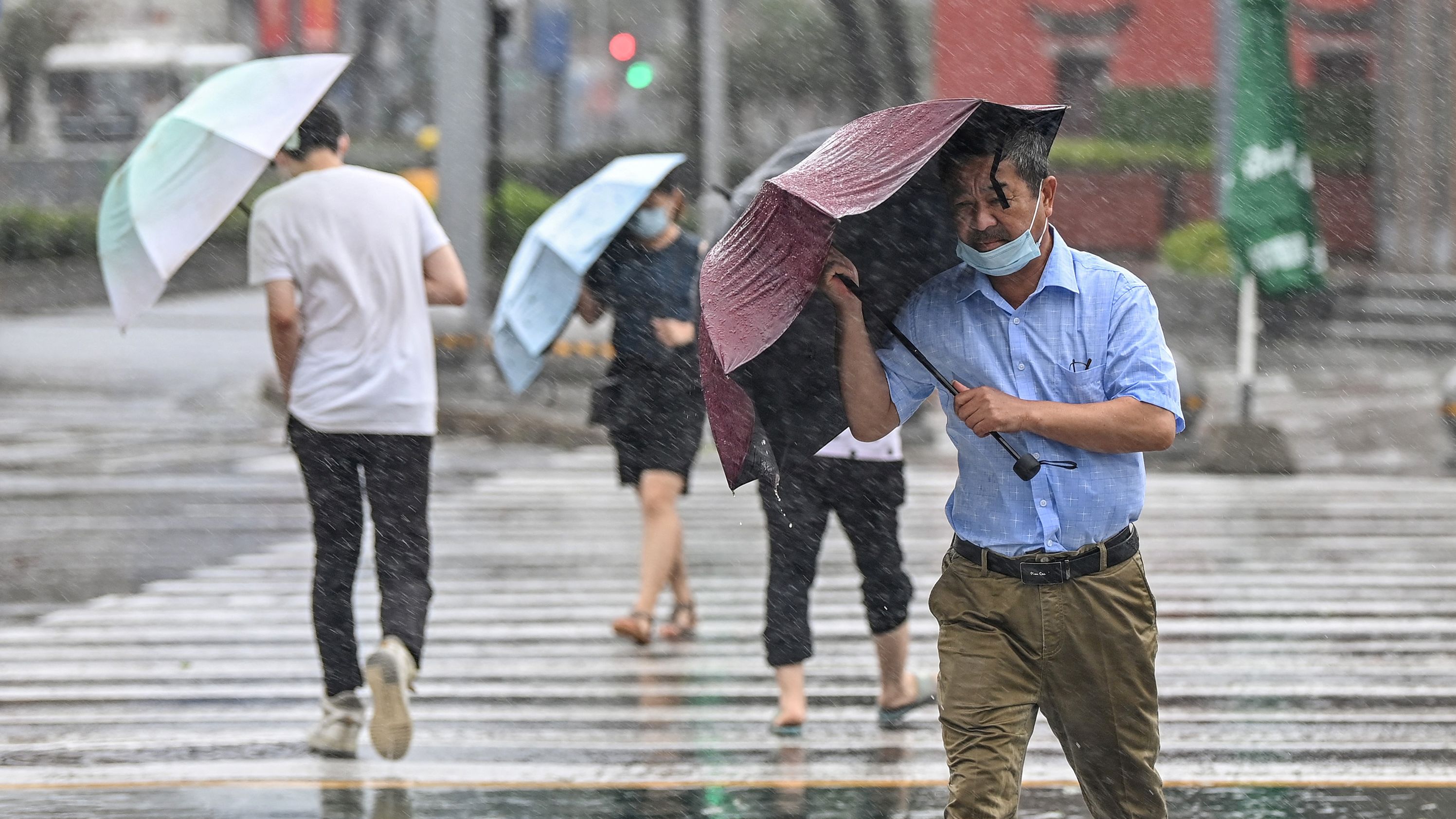 People cross the street in the wind and rain in Ningbo on July 25, as Typhoon In-Fa lashes the east coast of China.