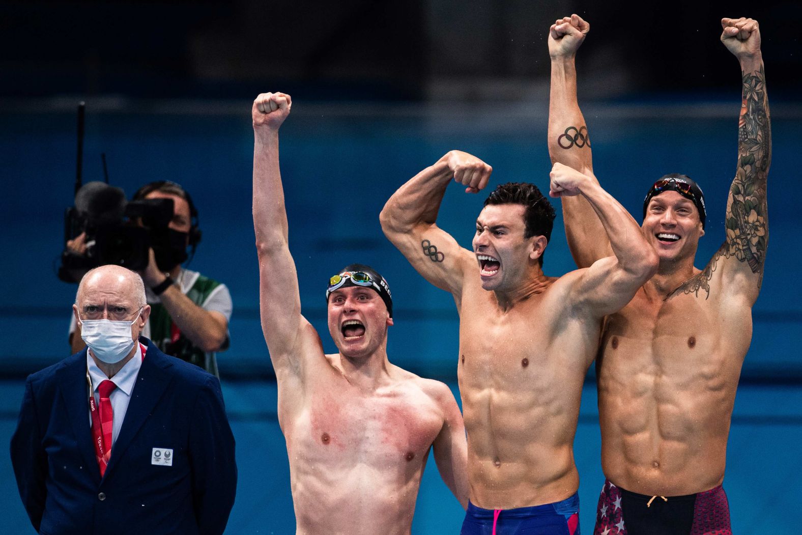 Three US swimmers — from right, Caeleb Dressel, Blake Pieroni and Bowen Becker — celebrate after <a href="index.php?page=&url=https%3A%2F%2Fwww.cnn.com%2Fworld%2Flive-news%2Ftokyo-2020-olympics-07-26-21-spt%2Fh_a2676f178c57545842ef135c0601906e" target="_blank">winning the 4x100-meter freestyle relay</a> on July 26. Not pictured is teammate Zach Apple, who swam the anchor leg.