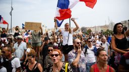 A protestor holds a placard reading "Freedom" while others wave French national flags during a demonstration against the compulsory vaccination for certain workers and the mandatory use of the health pass called by the French government, in Marseille, southern France on July 24, 2021. - Since July 21, people wanting to go to in most public spaces in France have to show a proof of Covid-19 vaccination or a negative test, as the country braces for a feared spike in cases from the highly transmissible Covid-19 Delta variant. (Photo by CLEMENT MAHOUDEAU / AFP) (Photo by CLEMENT MAHOUDEAU/AFP via Getty Images)