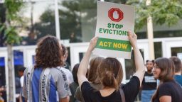 A woman holds a placard to stop evictions at a rally for housing reform.