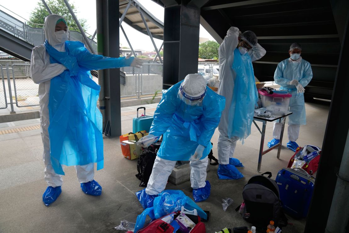 Health workers prepare their protective gear before a group of people infected with Covid-19 arrive at Rangsit train station near Bangkok on July 27.