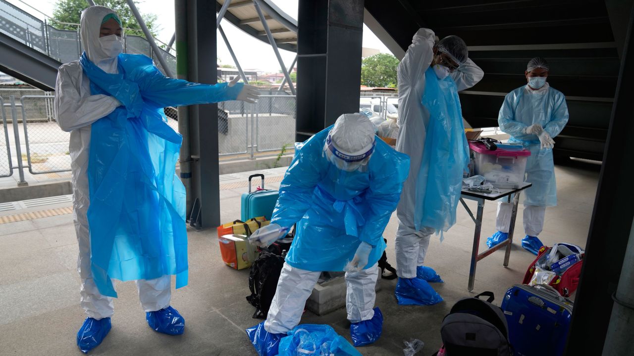 Health workers prepare their protective gear before a group of people infected with Covid-19 arrive at Rangsit train station near Bangkok on July 27.