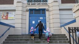 A father leading his daughters into the first day of school at an elementary school in Brooklyn, Sept. 21, 2020. They were turned away and told school would start next week for grade levels. (Kirsten Luce/The New York Times/Redux)
