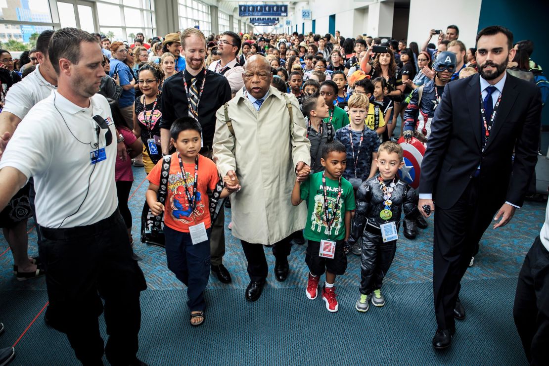 Rep. John Lewis, dressed as his younger self, with Andrew Aydin, his aide and co-author, at right, leads a group of children in a march across the San Diego Convention Center during the 2016 Comic-Con convention.
