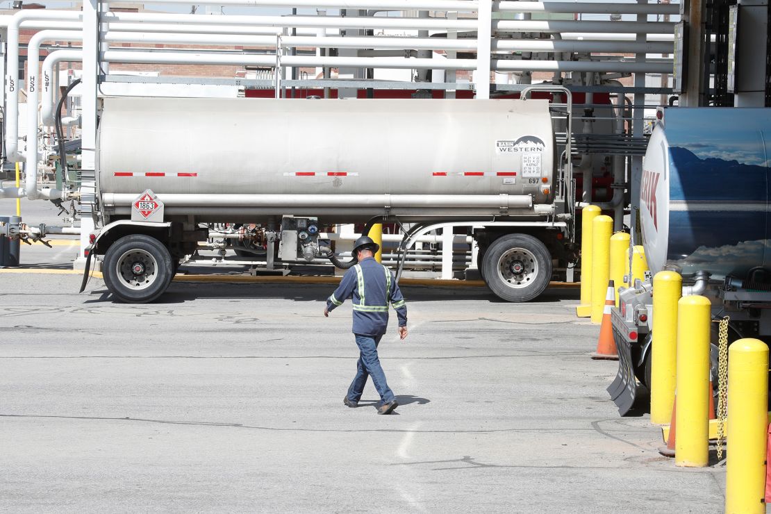 A worker walks by tanker trucks that are being filled with gasoline at an oil refinery in Utah.