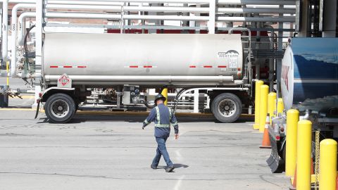 A worker walks by tanker trucks that are being filled with gasoline at an oil refinery in Utah.