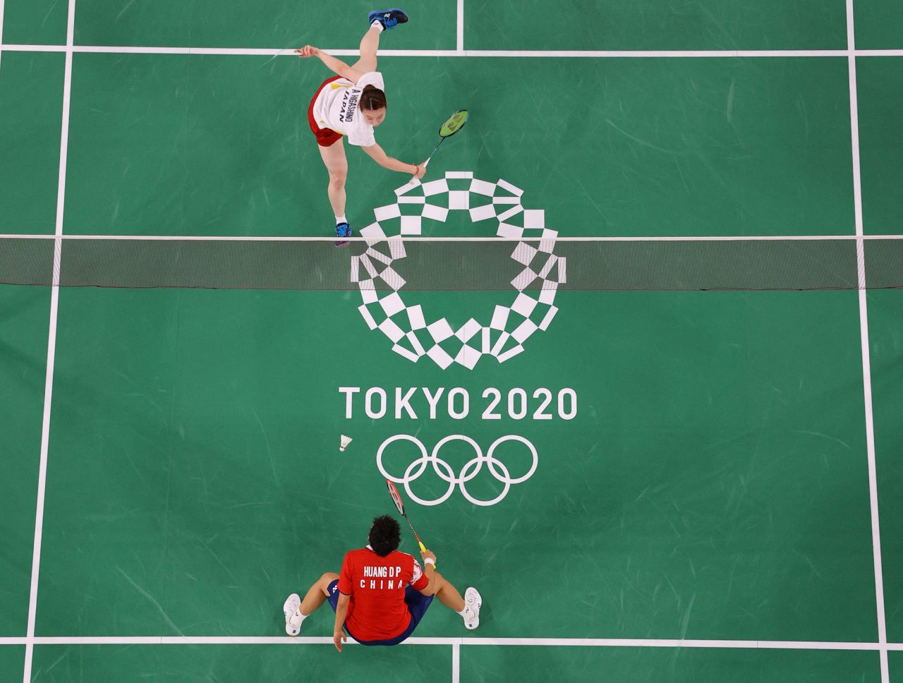 Japanese badminton player Arisa Higashino, top, hits a shot toward China's Huang Dongping in a mixed-doubles semifinal on July 29.
