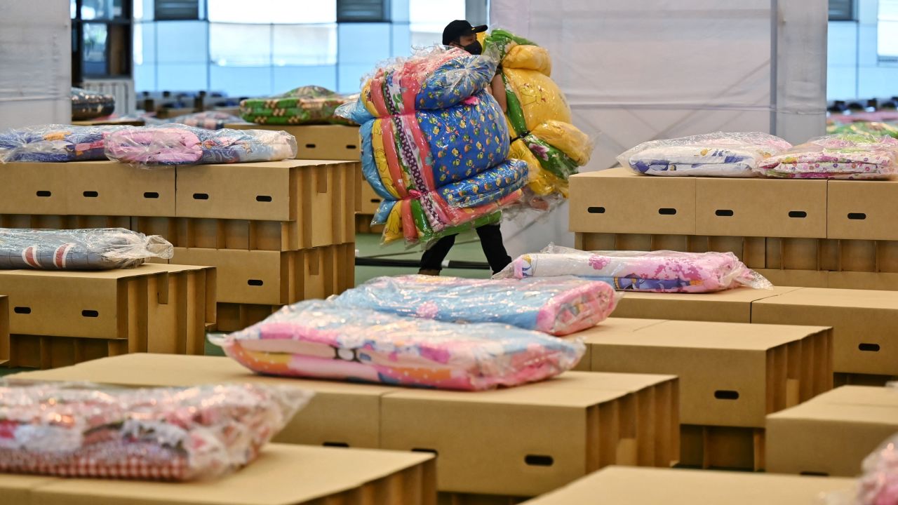Workers prepare mattresses and blankets for the cardboard beds at the Covid-19 field hospital inside a warehouse at the Don Mueang International Airport in Bangkok on July 27, 2021.