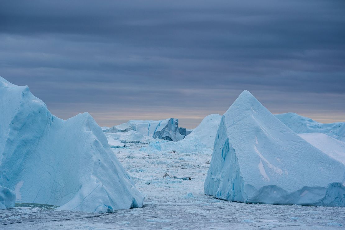 Warmer coastal water melts the Greenland ice sheet around the edges, breaking off massive icebergs that contribute to sea level rise.